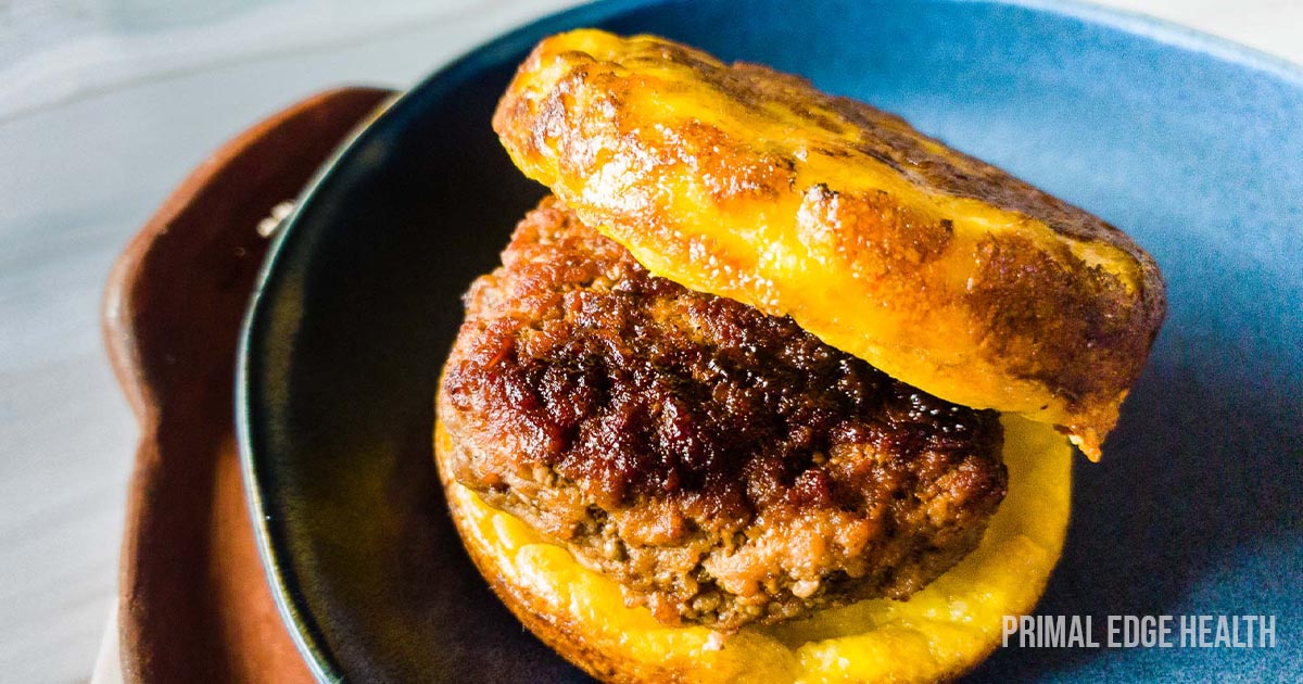 A close-up of a juicy hamburger with melted cheese and a glossy bun on a blue plate.