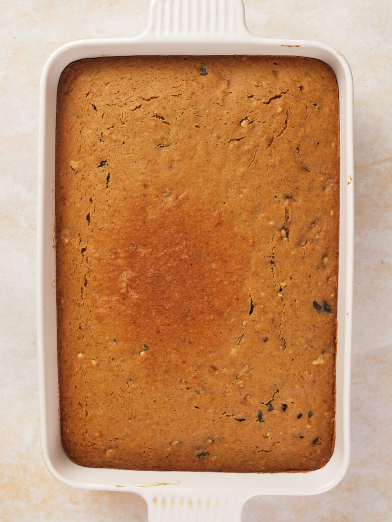 A rectangular baked dish with a golden-brown crust sits in a white ceramic baking dish.