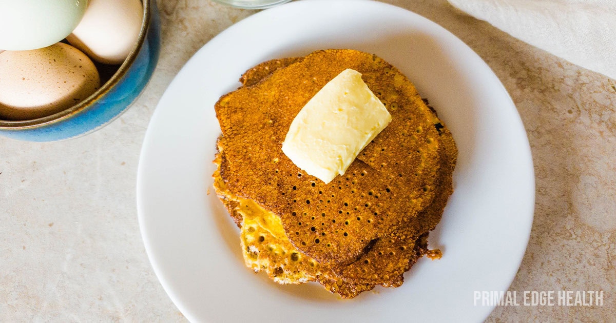 A stack of cream cheese pancakes on white plate with butter.