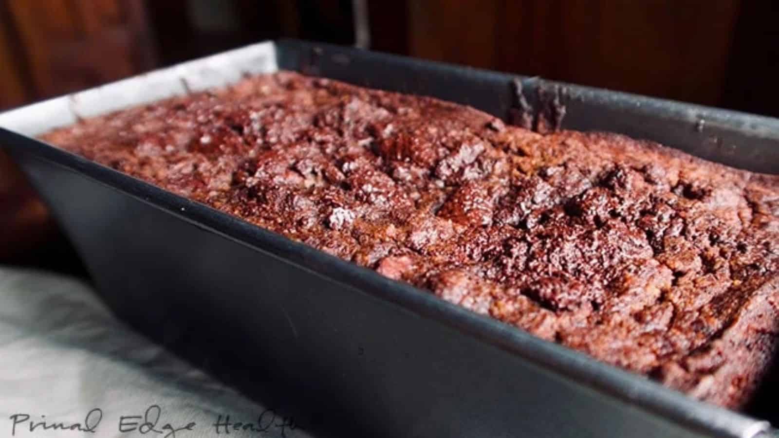 A close-up of a freshly baked loaf of chocolate pumpkin bread in a black metal pan.