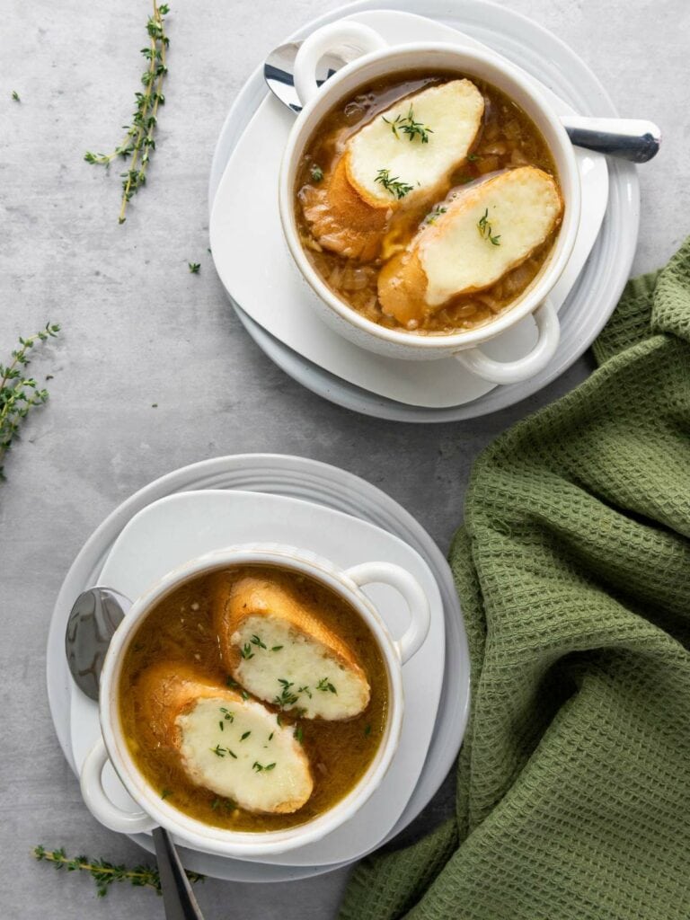 Two bowls of French onion soup topped with toasted bread and melted cheese.