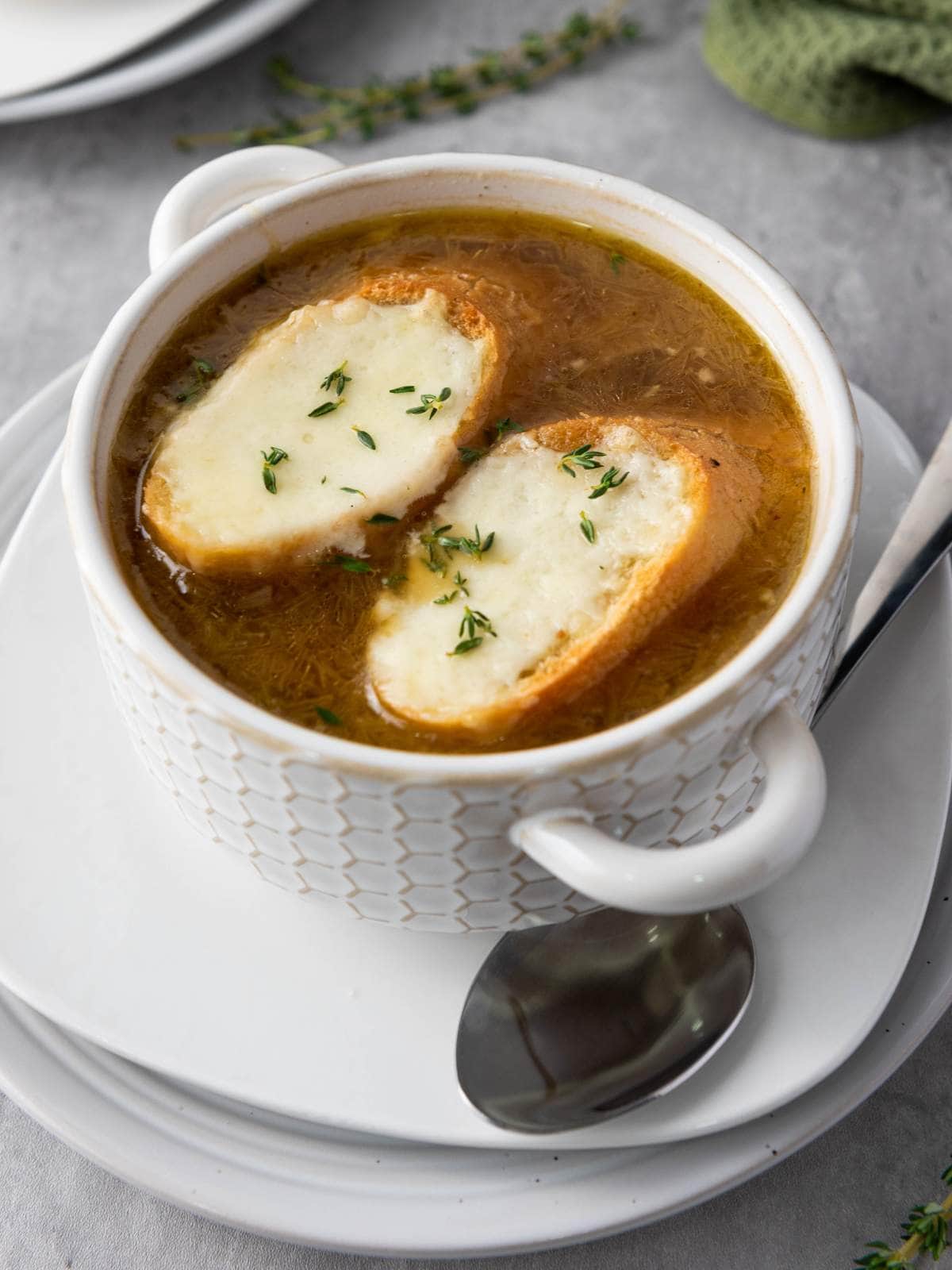 A bowl of French onion soup topped with two slices of toasted bread and melted cheese.