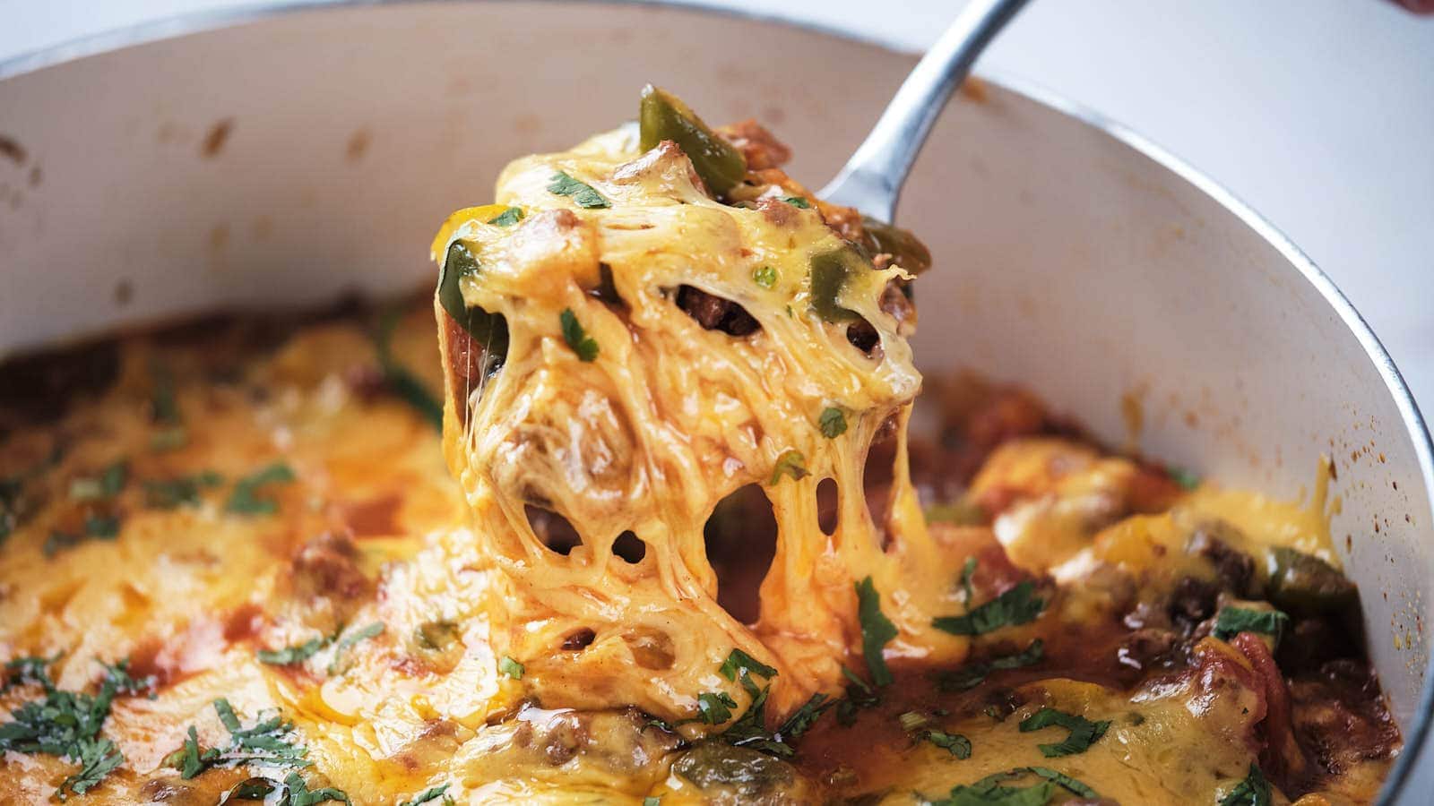 A close-up of ground beef taco skillet being served with a metal spoon.