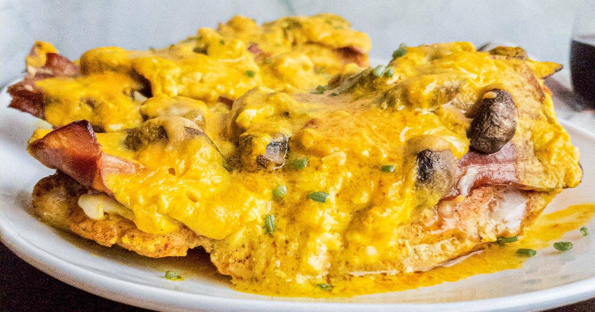 Close-up of a plate with alice springs chicken, topped with mushrooms and chives.