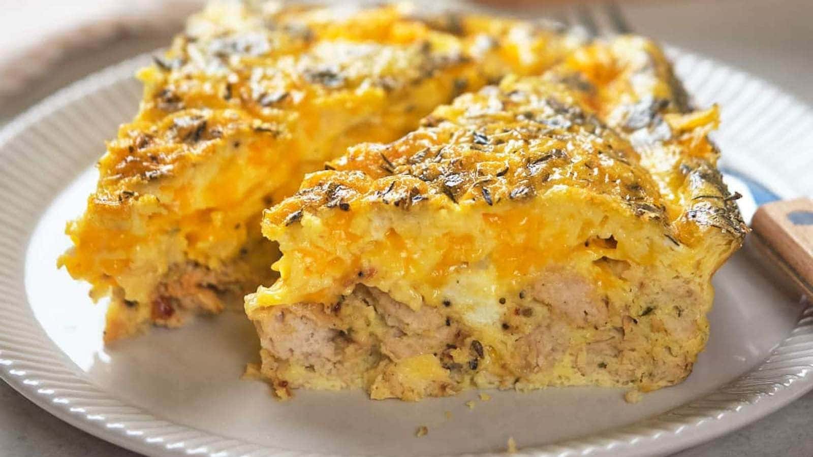 Two slices of cheesy breakfast casserole on a white plate with a fork in the background.