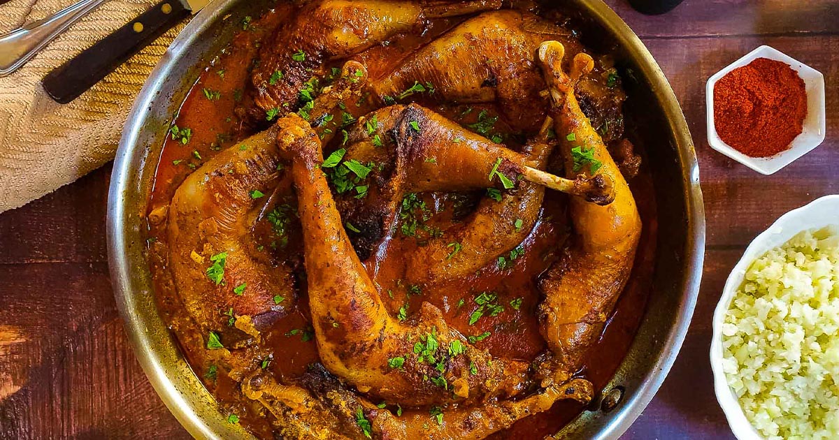 Chicken paprikash in skillet on a wooden surface.