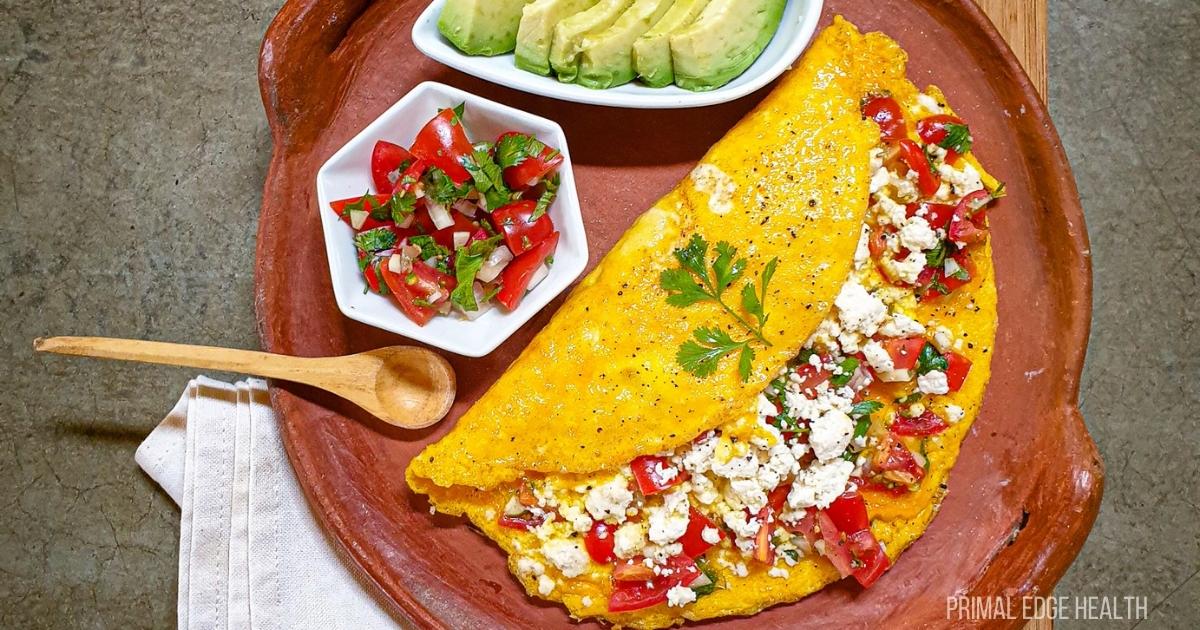 Mexican omelette folded with queso fresco and salsa on earthen serving tray.