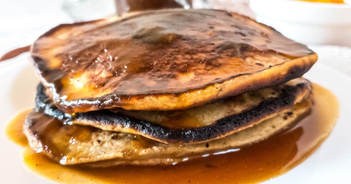 A stack of pancakes with pumpkin spice syrup on a plate.