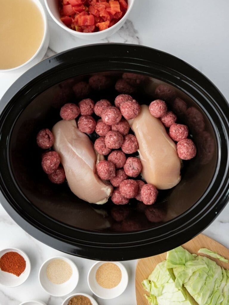 Chicken breasts and meatballs in a slow cooker.