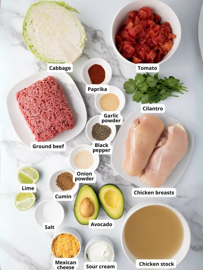 Various ingredients for taco soup labeled on a marble surface.