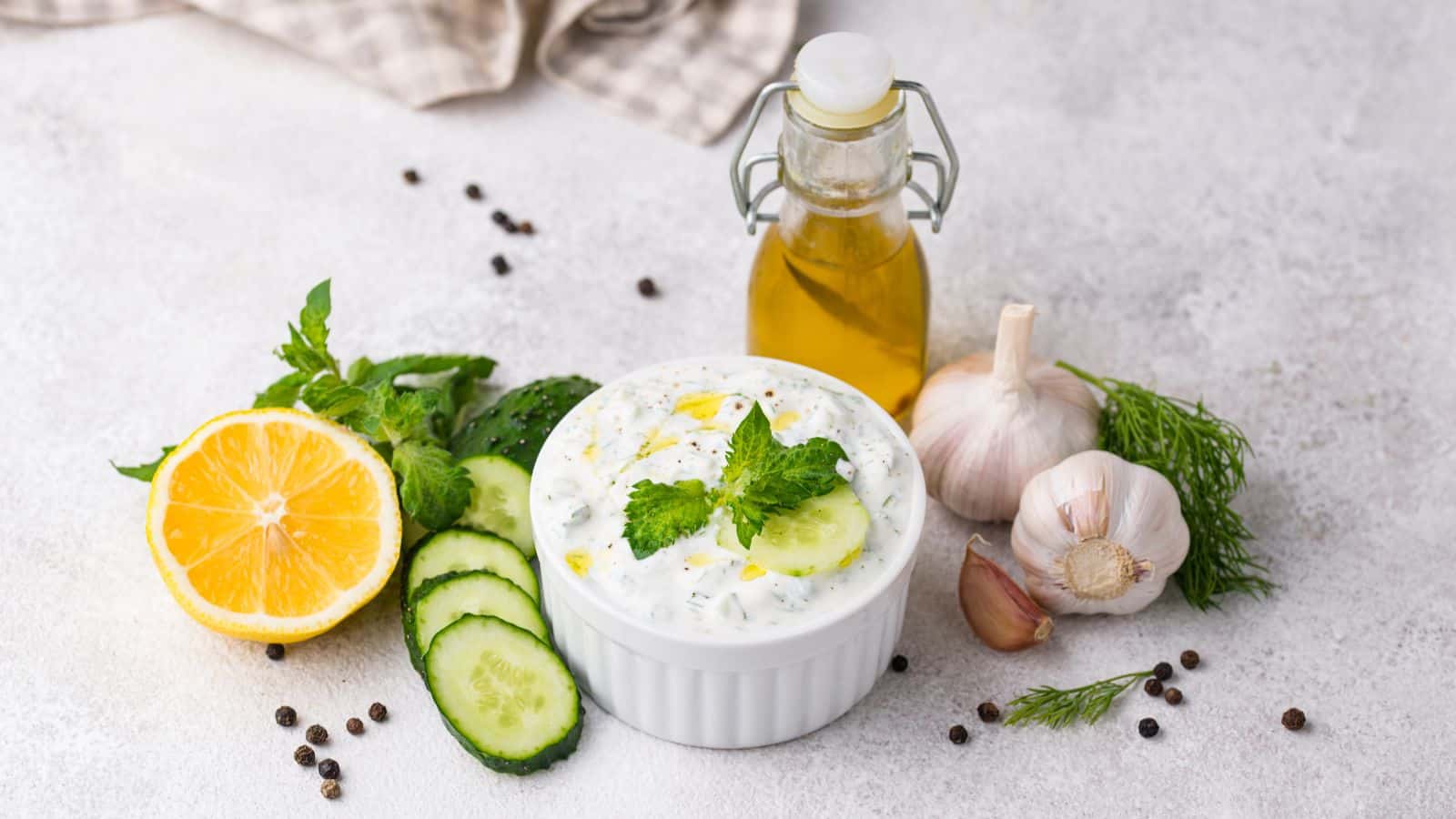 Greek tzatziki sauce in white cup with lemon cucumber garlic.