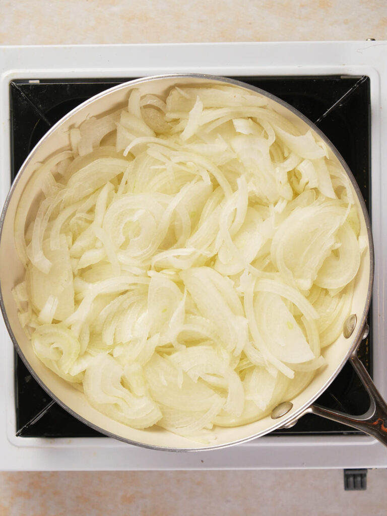 A pan filled with sliced onions on a stovetop.