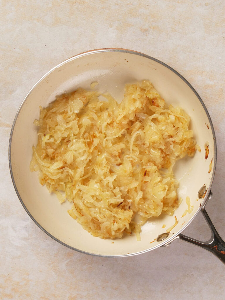 Pan of sautéed onions on a light surface.