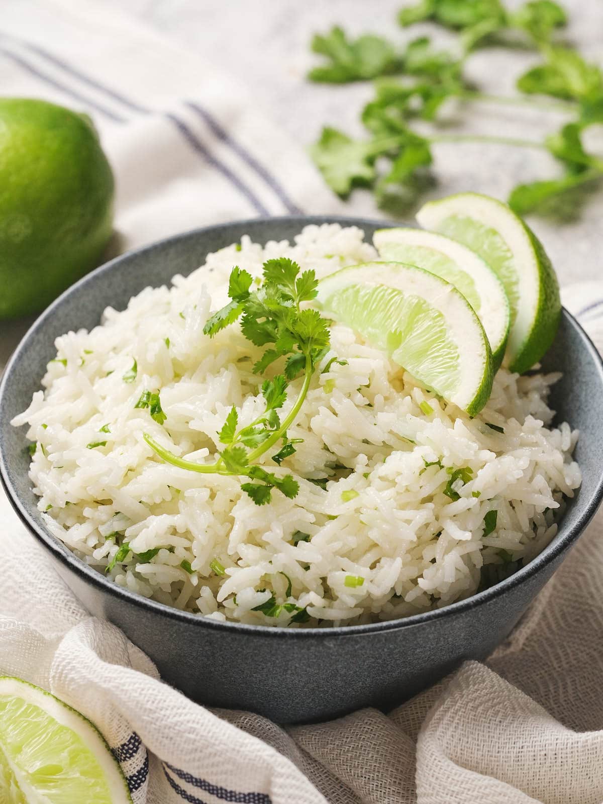 A bowl of chipotle rice garnished with cilantro and lime slices, placed on a cloth.