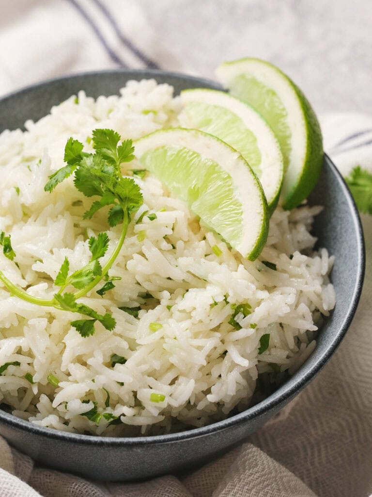 A bowl of chipotle rice garnished with cilantro and lime slices.