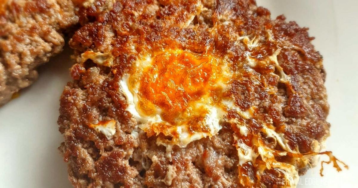 A plate of meat burgers with an egg on top.