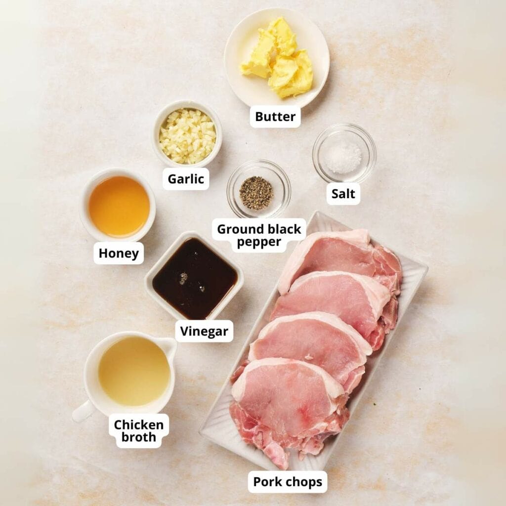 Ingredients for honey glazed pork chops are arranged on a light surface with labels identifying each item.