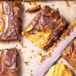 Close-up of sliced peanut butter brownies with caramel swirl on parchment paper.