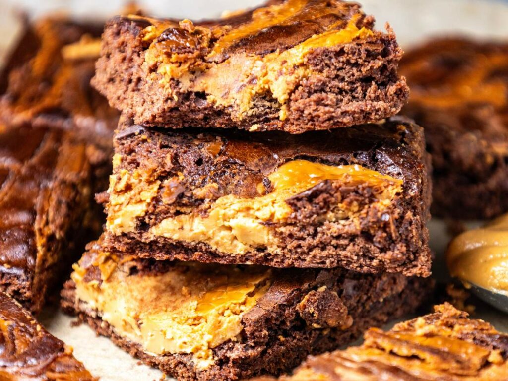 Three stacked peanut butter brownies with a marbled pattern on a surface.