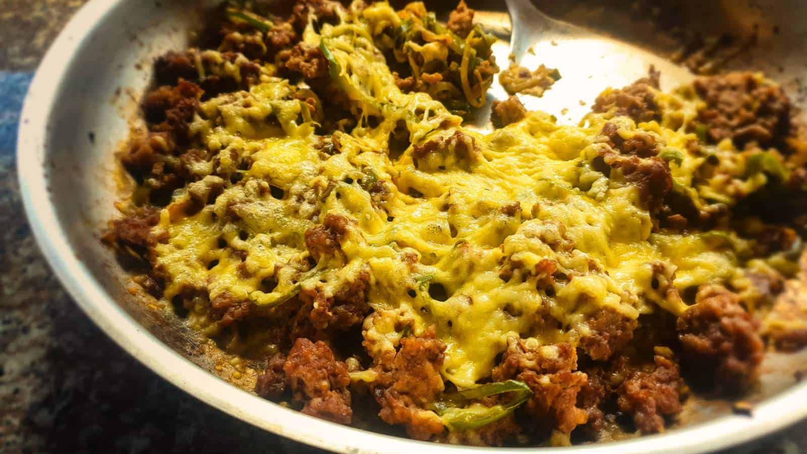 Lower left corner of Philly Cheesesteak casserole in glass baking dish cooling on rack.