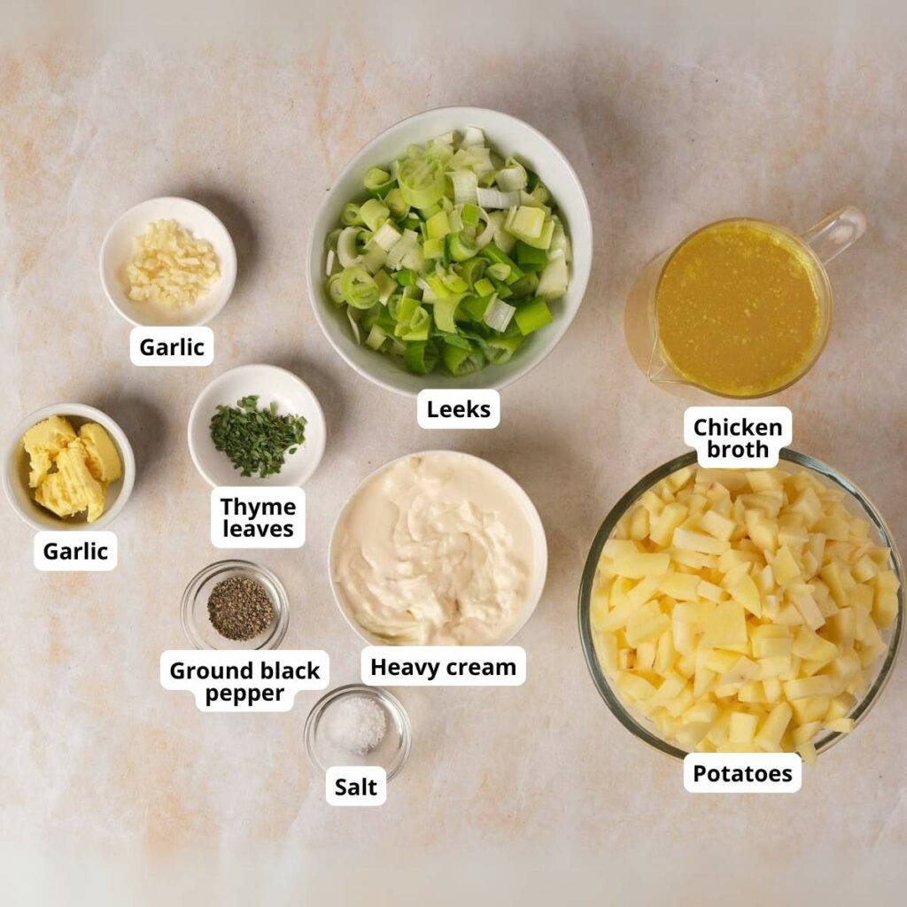 Various ingredients for potato and leek soup arranged in bowls on a light surface.