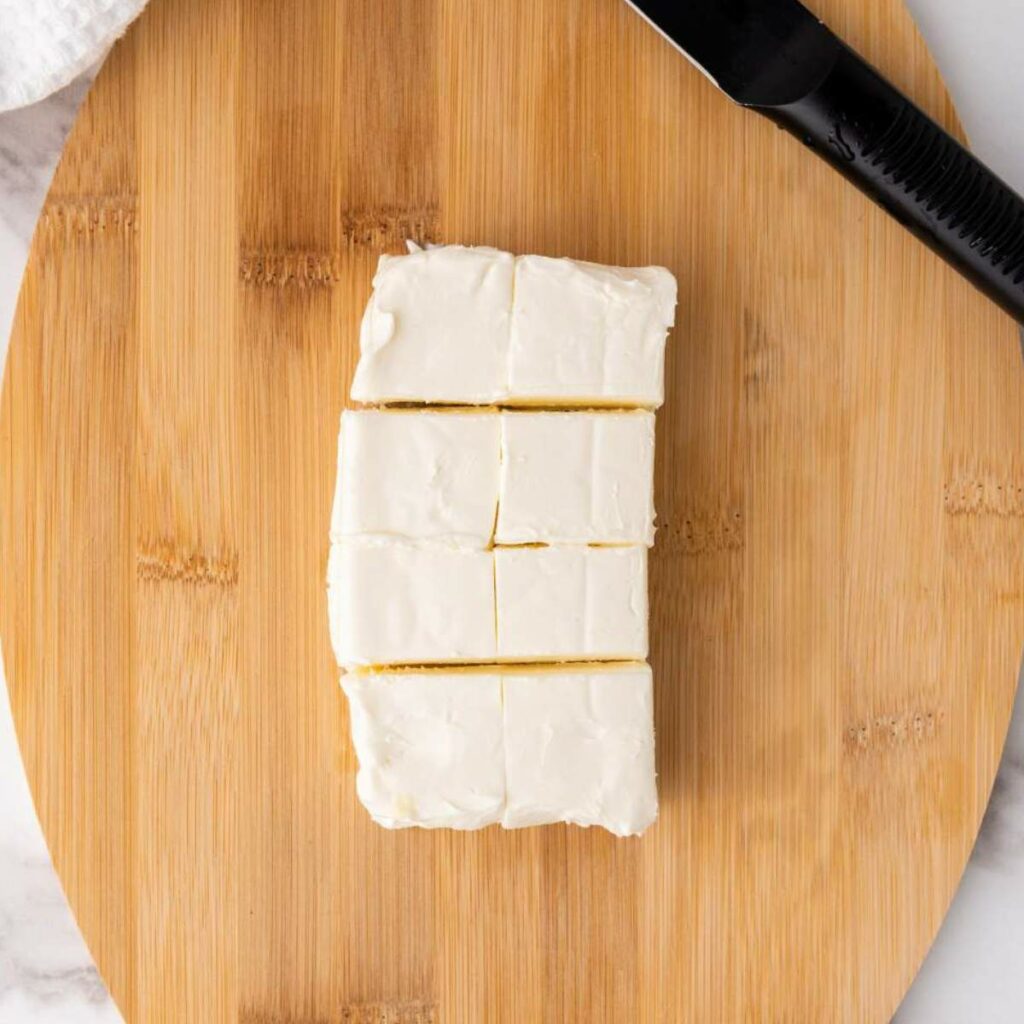 Sliced cake with white frosting on a wooden cutting board.