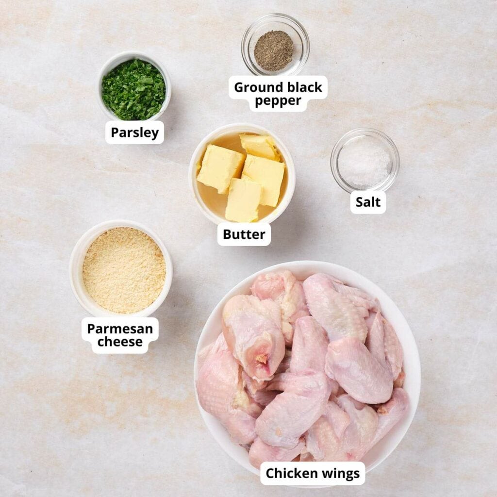 Ingredients for parmesan and garlic wings arranged on a surface, each labeled with text.